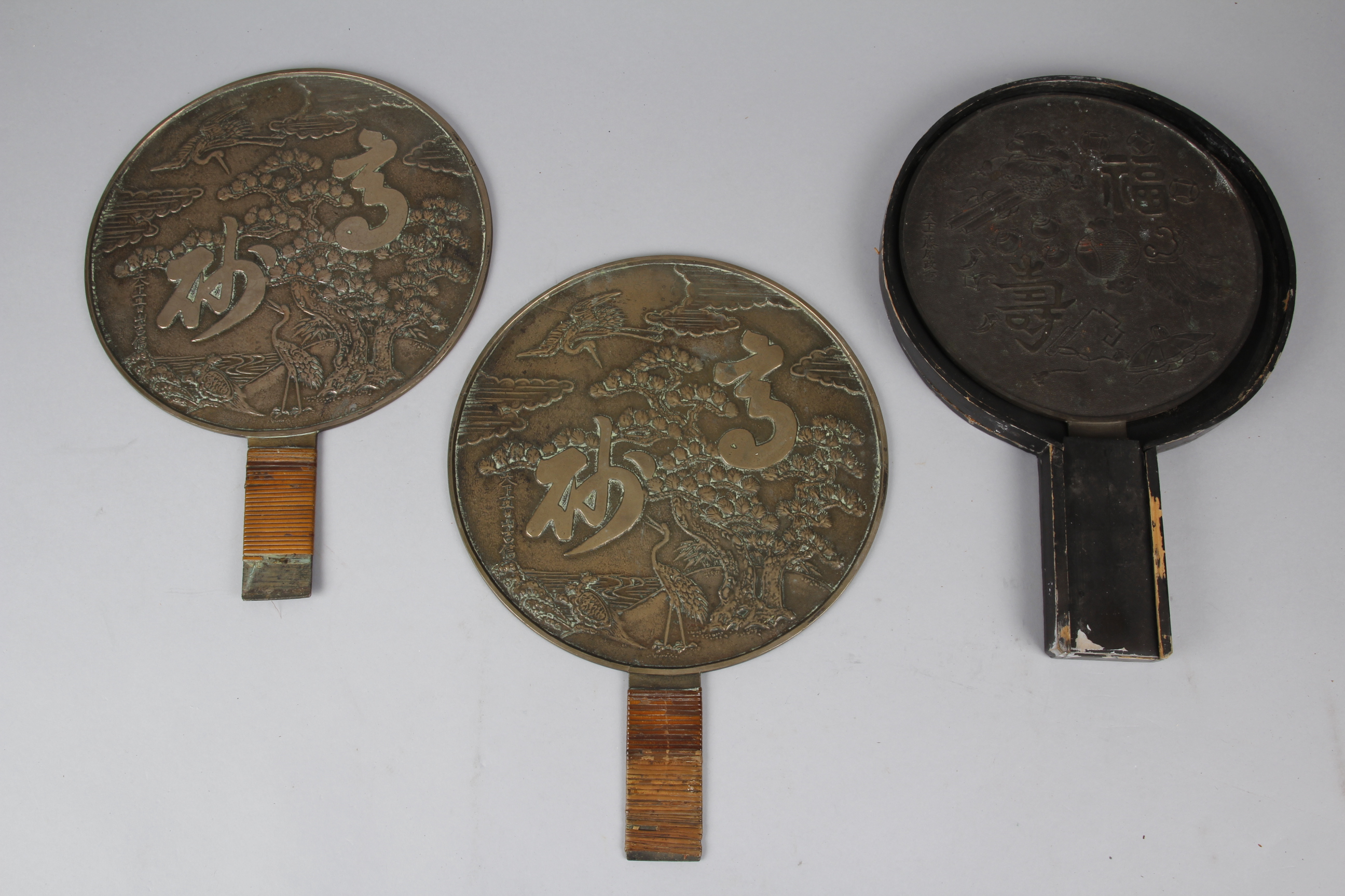 Three Japanese Bronze ‘Magic Mirrors’, one in a lacquered case, 205mm wide, lid missing, and two