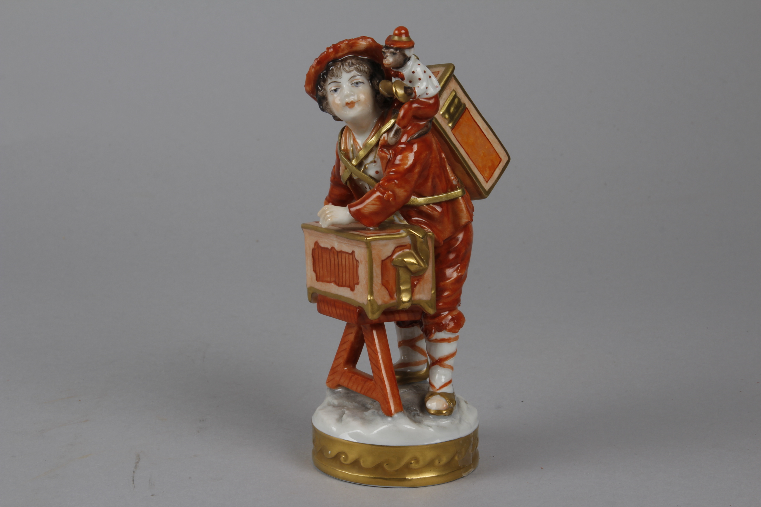 A Continental Porcelain Figurine of an Itinerant Magic Lanternist, the boy with a magic lantern on