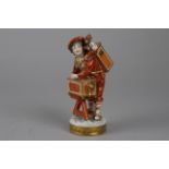 A Continental Porcelain Figurine of an Itinerant Magic Lanternist, the boy with a magic lantern on