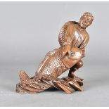 A Chinese boxwood carving, modelled as a Chinese fisherman hauling an over sized carp from a rough