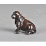 A Japanese hardwood netsuke, carved as a long eared spaniel with black glass eyes, 5 cm