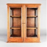 An oak three glass collectors cabinet, the panelled doors opening to reveal two adjustable