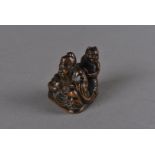 An Edo period Japanese carved wood netsuke, modelled as Shoki guarding the emperor on a triangular