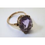 A gold ring set with a large single amethyst