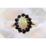 A 9ct gold ring set with a central opal and surrou