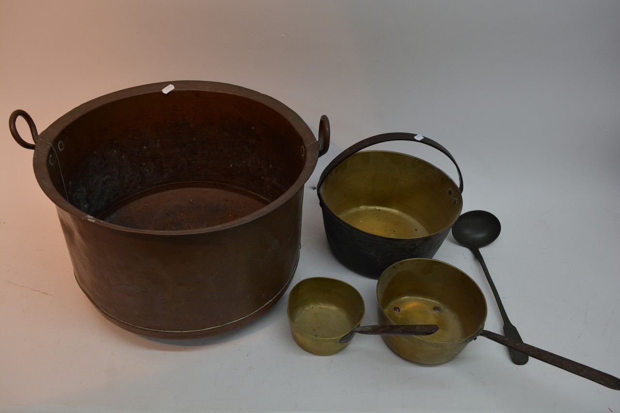 A large copper pot, two brass saucepans, spoon and