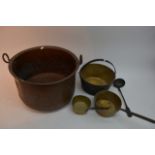 A large copper pot, two brass saucepans, spoon and