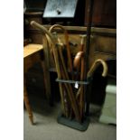 A cast iron stick stand containing walking sticks.