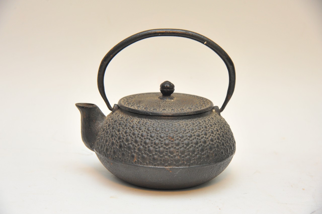 A Japanese cast iron teapot decorated in relief