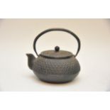 A Japanese cast iron teapot decorated in relief