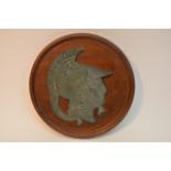 A metal plaque of a Roman soldier on wooden wall m