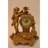 A gilt metal mantel clock flanked with a cherub ho