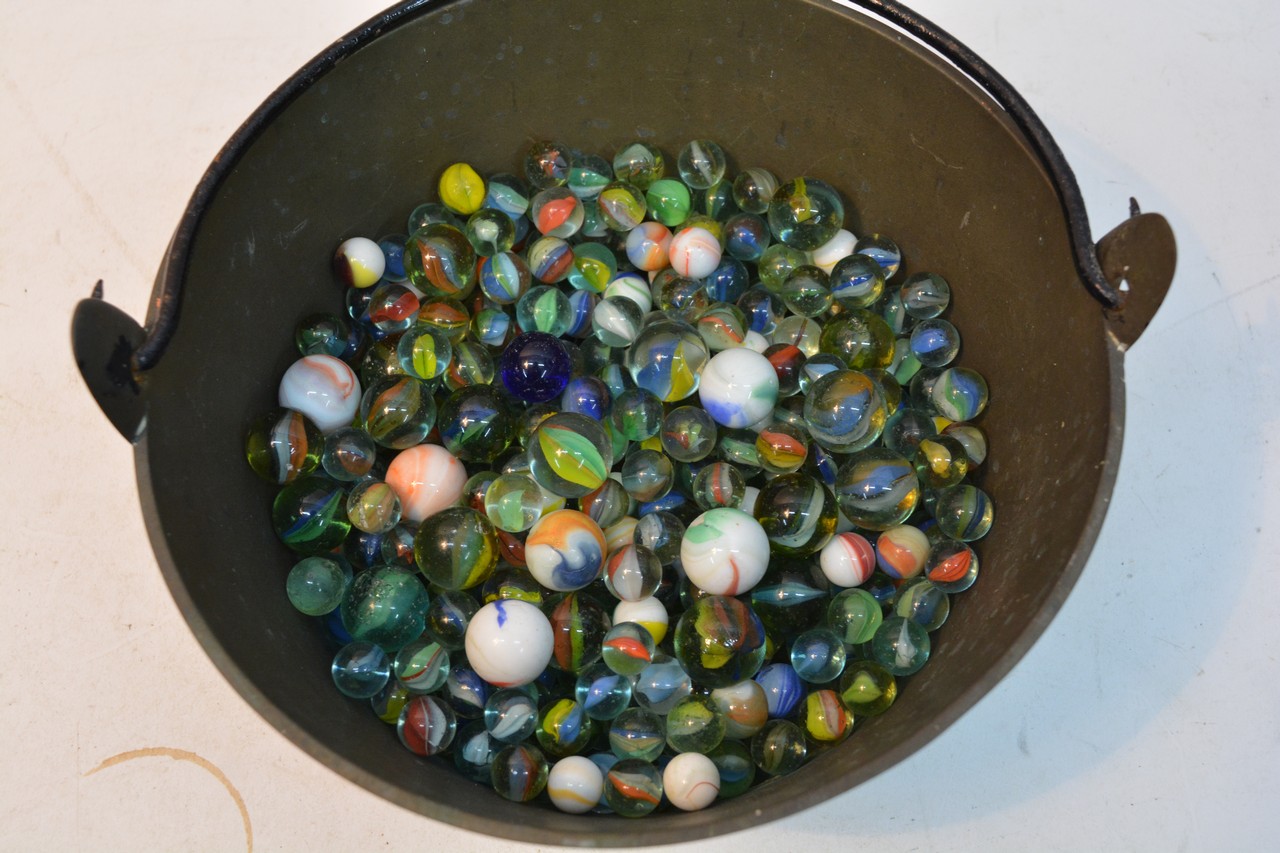 A brass bowl containing old marbles