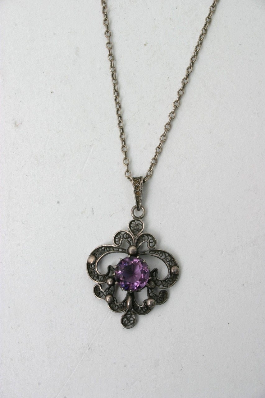 A vintage silver necklace with attached amethyst p