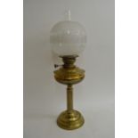 A brass oil lamp with clear and frosted glass shad