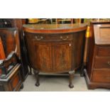 A bow fronted cabinet with a single drawer and cup