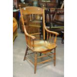 An oak open arm chair with stick back solid seat o