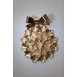 A 9ct gold brooch depicting cherubs set with rubies within a four leaf clover surround.