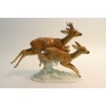 A ceramic figural group of two leaping deer.