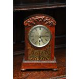 A rosewood mantel clock with brass inlaid decorati