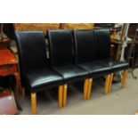 A set of four modern black leather dining chairs.
