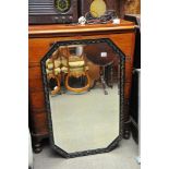 An octagonal wall mirror with carved black frame.