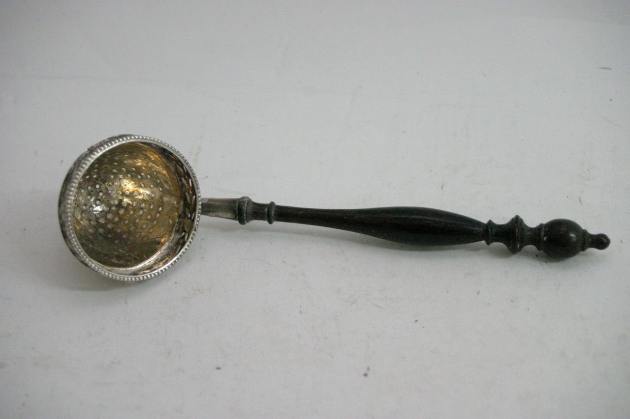 A continental silver straining ladle with turned w