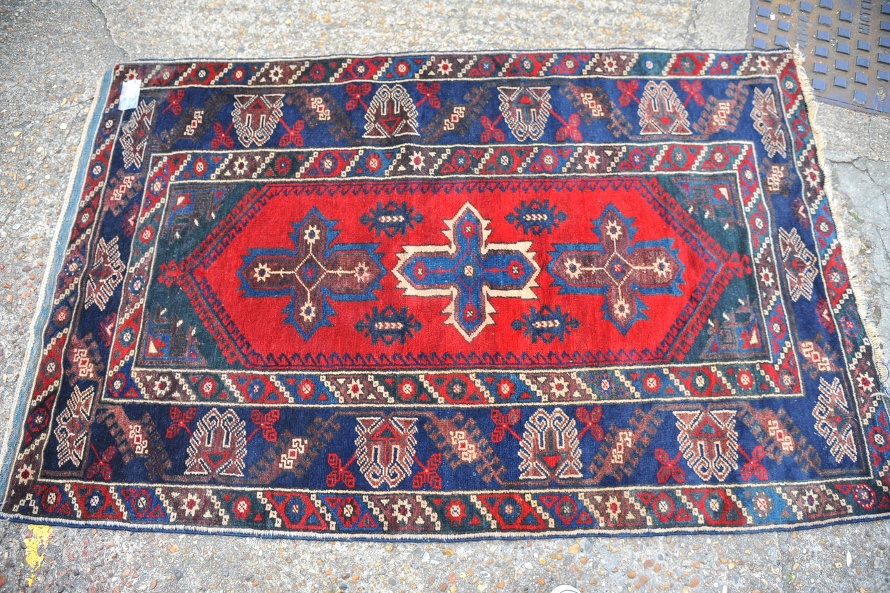 An antique rug in blue, red and cream, approx 112c