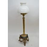 An early 20th Century table lamp with brass column, triple ram's head base and white glass shade,