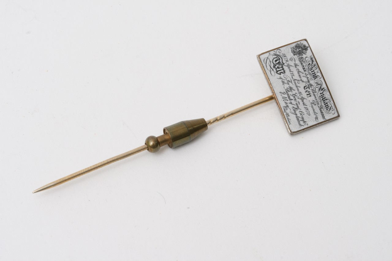 A tie pin in the form of a Victorian bank note.