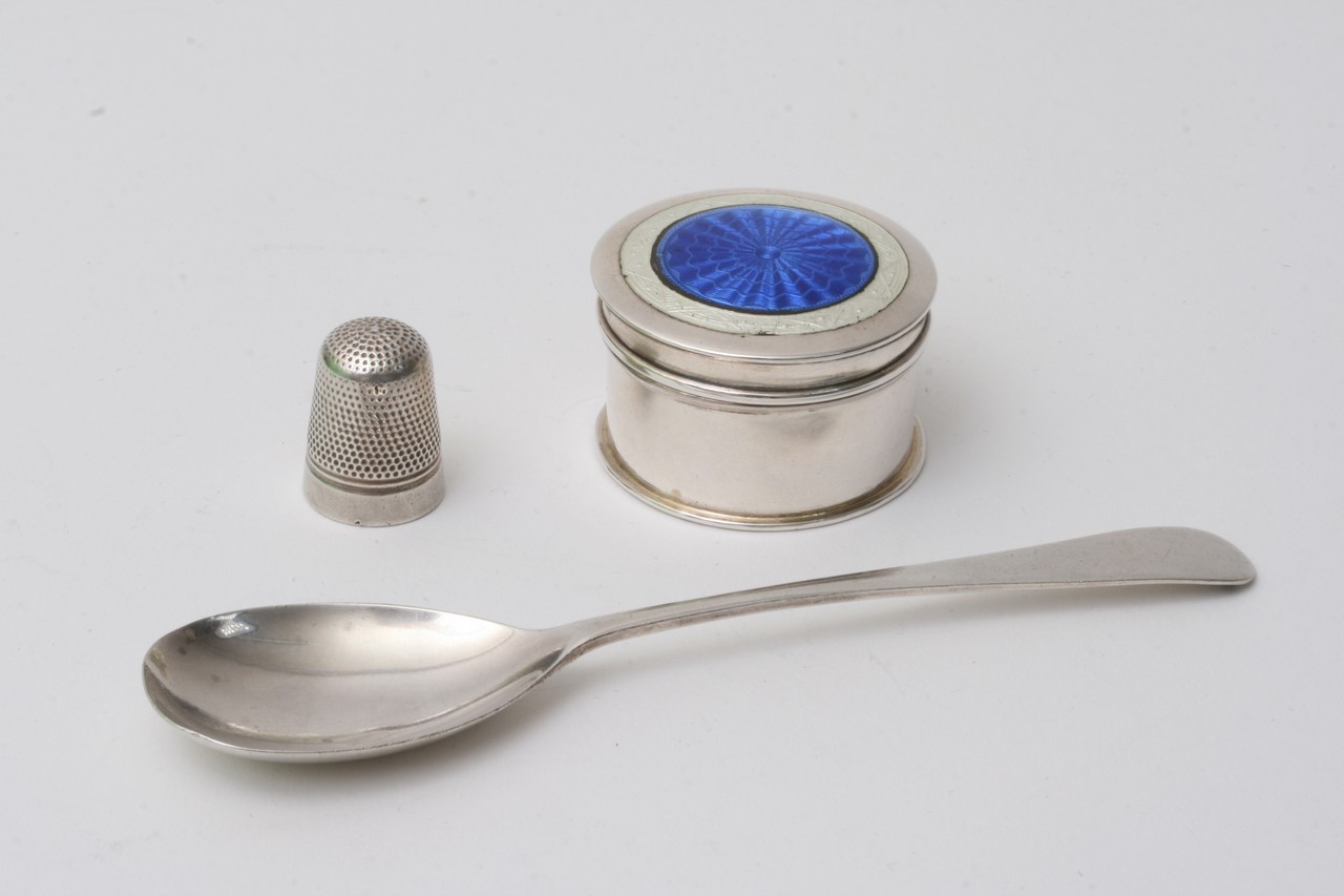 A small silver and enamel pill box, spoons, and th