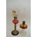 A Victorian oil lamp with cranberry glass reservoir, painted shade and chimney plus another oil lamp