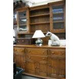 An Ercol type dining room dresser, the base having three cupboards of various size and four drawers,