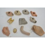 A collection of ancient Egyptian pottery artefacts including oil lamps scarabs and parts of pots