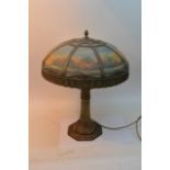 A large Art Deco gilt metal lamp, the coloured glass shade painted with a landscape, one replacement