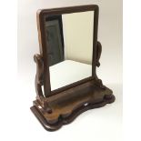 An oblong, dark wood free standing mirror with cur