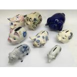 A collection of 8 ceramic piggy banks.