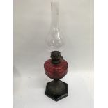 A Victorian oil lamp with cranberry glass well