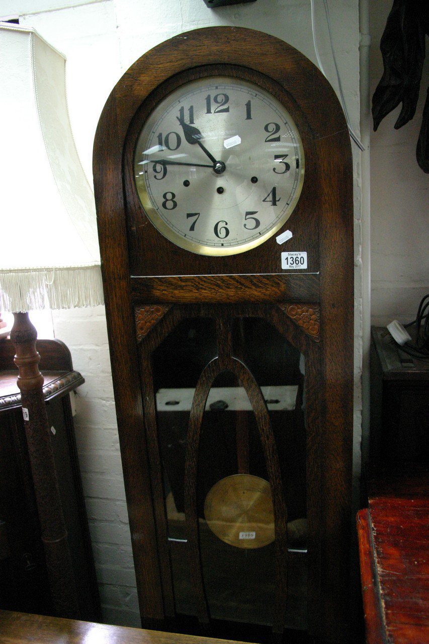 An oak 1930s longcase clock with visible pendulum