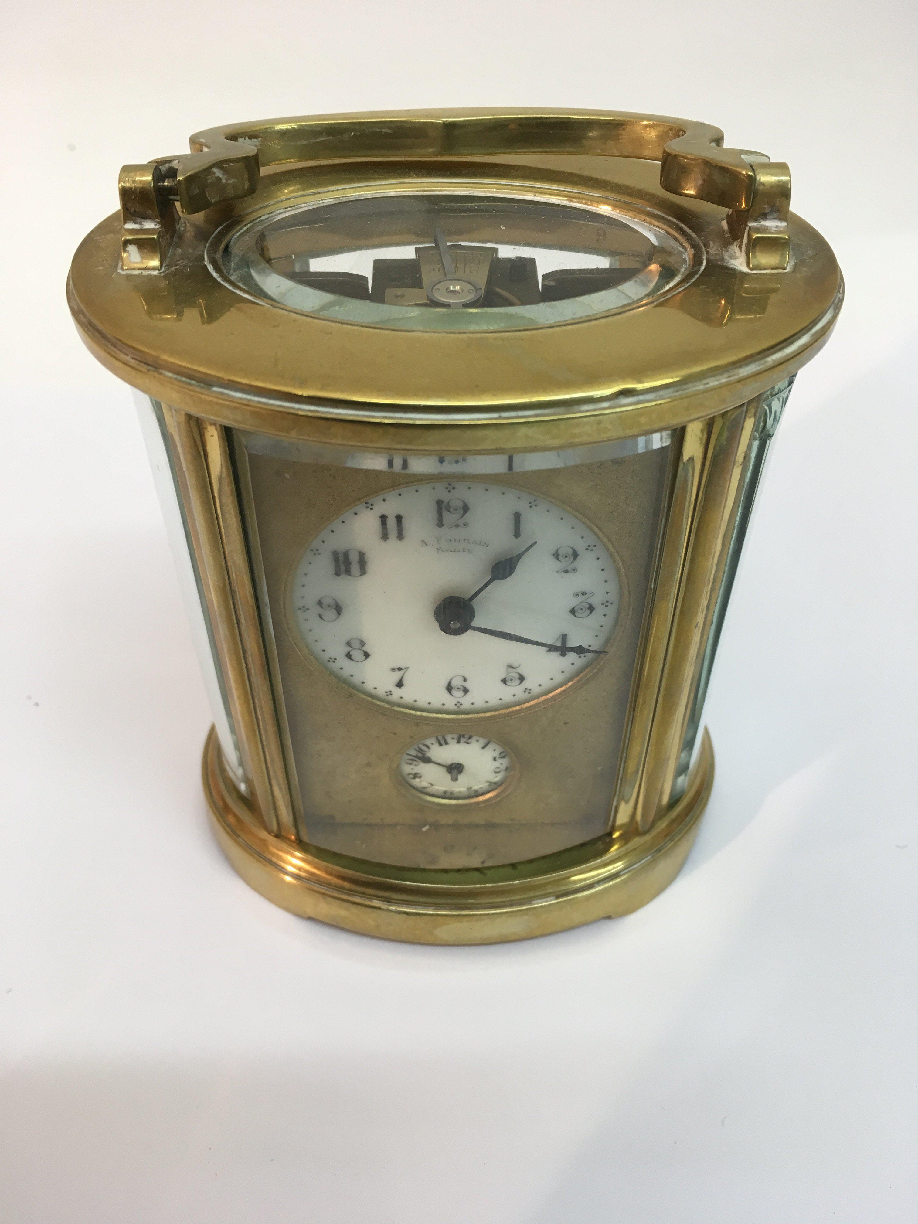 A brass oval carriage clock the enamel dial with A