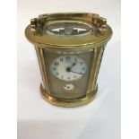 A brass oval carriage clock the enamel dial with A