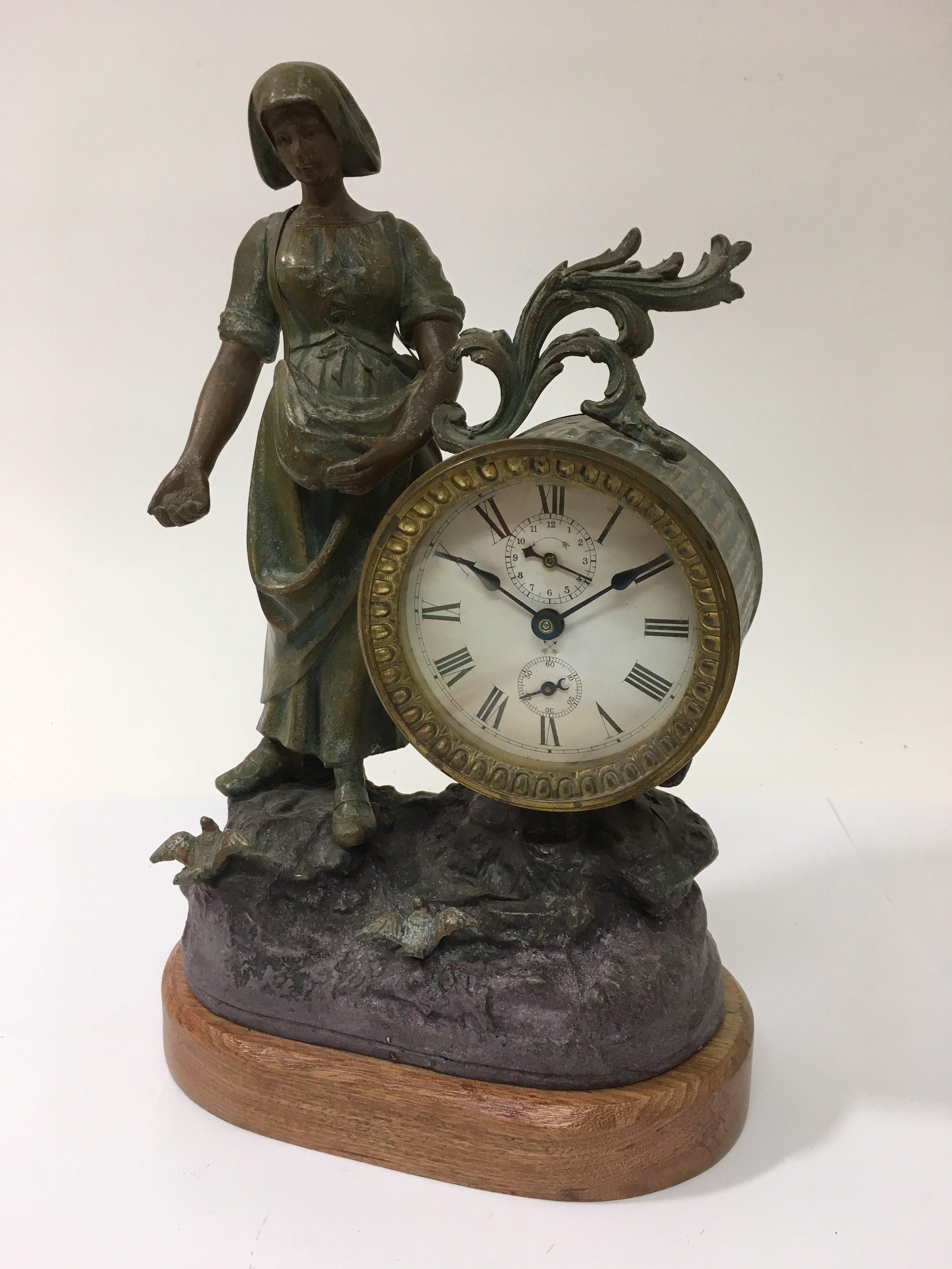 A spelter figural clock of a woman feeding birds,