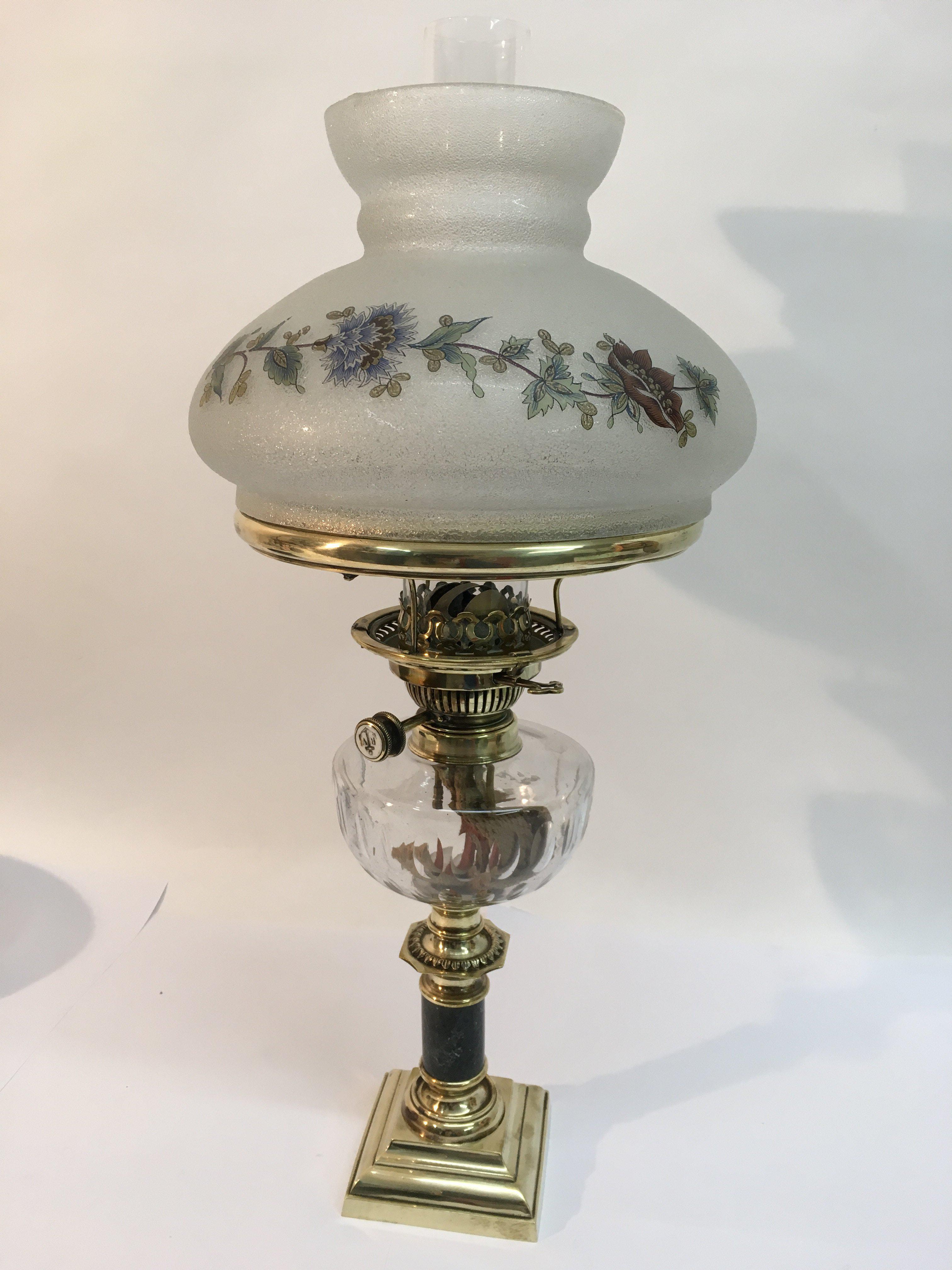 A brass oil lamp with a floral decorated frosted g