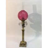 A brass oil lamp with crackleware cranberry glass