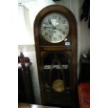 An oak 1930s long case clock with visible pendulum