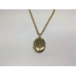 A 9ct gold oval locket with attached 9ct gold chai