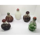 Five glass snuff bottles, four with coloured relie