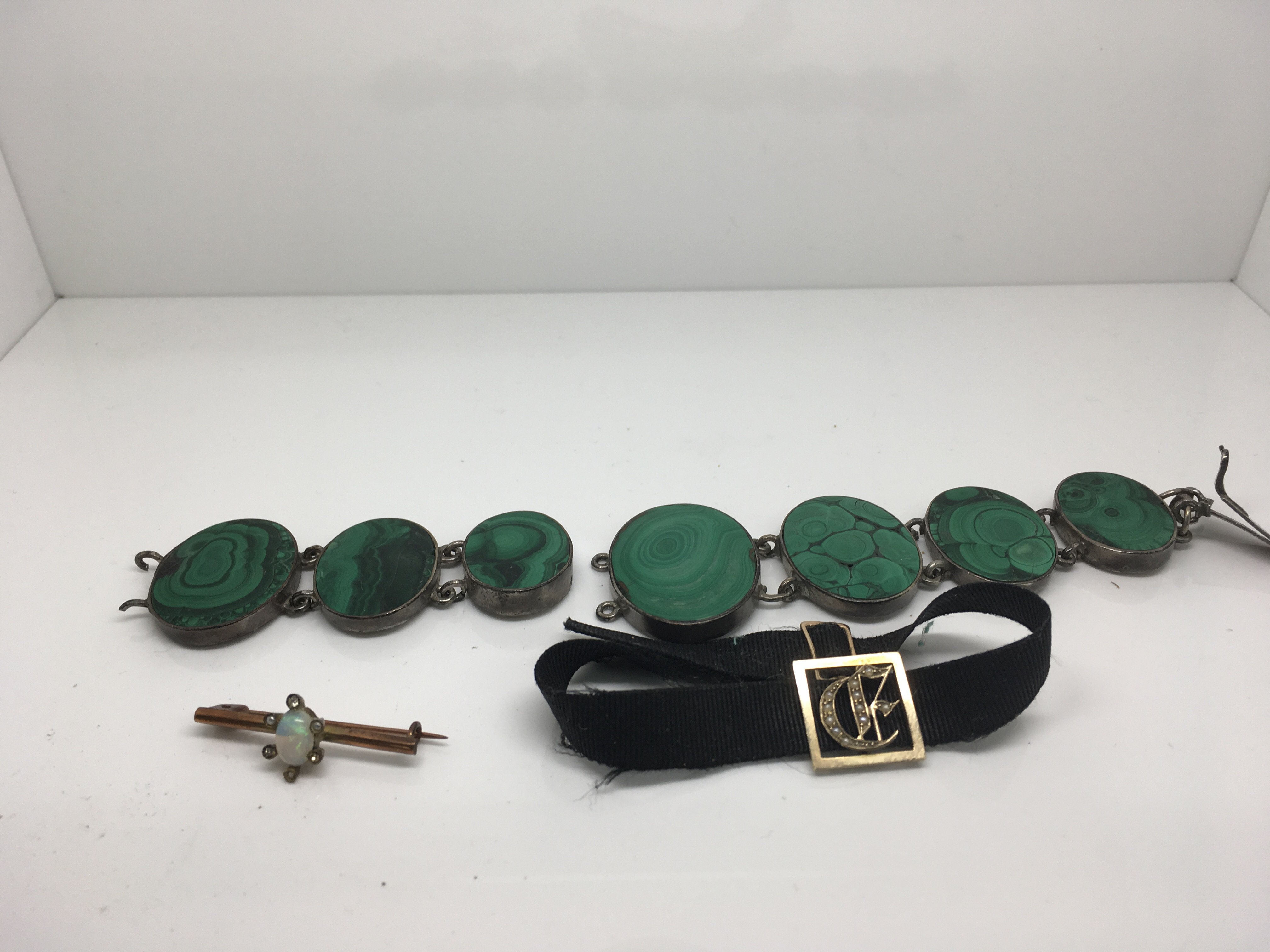 An Edwardian broach inset with opal a malachite bracelet and a black band with attached seed