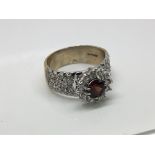 a 9ct gold ring set with a garnet stone flanked by smaller stones, ring size Q.