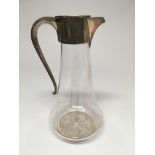 A glass claret jug with silver lid collar and hand